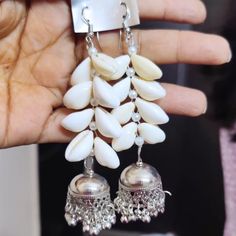 Embrace your love for nature and unique craftsmanship with our Bohemian Cowrie Shell Earrings. Each earring features carefully selected white cowrie shells arranged in a beautiful cascading pattern, culminating in an ornate oxidized silver bell that adds an elegant jingle with every movement. These earrings are a perfect blend of natural beauty and artisanal charm, ideal for enhancing any outfit with a touch of boho-chic elegance. Materials Used: Cowrie Shells: Naturally harvested white cowrie s Adjustable Traditional Earrings For Beach, Bohemian Sterling Silver Jewelry With Latkans, Bohemian Sterling Silver Danglers For Festive Occasion, White Spiritual Dangle Earrings, Festive Bohemian Sterling Silver Danglers, Spiritual White Dangle Earrings, Traditional Nickel-free Earrings For Beach, Bohemian Bridal Earrings With Latkans In Silver, Bohemian Silver Bridal Earrings With Latkans