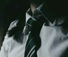 a man wearing a white shirt and black tie with his hands in his pockets while looking out the window