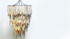 a chandelier made out of shells hanging from the ceiling in front of a white wall