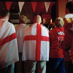 several people in red and white robes are standing near each other with flags on them