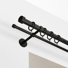 a black coat rack with four hooks on the top and one hanging from it's side