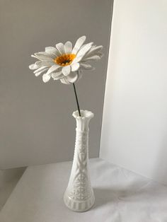 there is a white vase with a flower in it