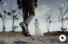 a woman in a wedding dress standing next to a man with his foot on the ground