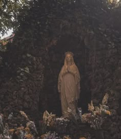 a statue in the middle of a garden surrounded by flowers