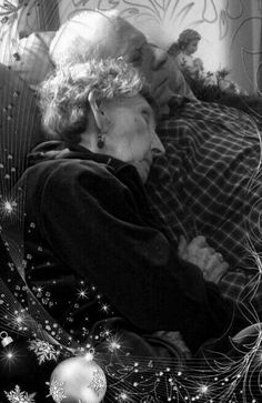 black and white photograph of two people sleeping on a bed with christmas decorations around them