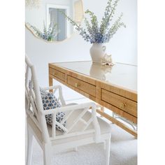 a white chair sitting in front of a table with flowers on it and a mirror behind it