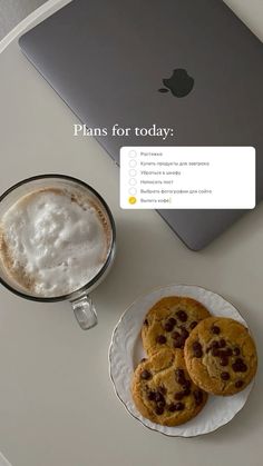 two cookies on a plate next to a cup of coffee and an apple macbook