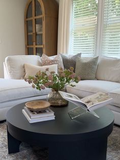 a living room filled with furniture and flowers on top of a coffee table in front of a window