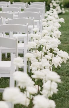 rows of white chairs lined up in the grass with flowers growing between them on each side