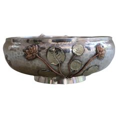 a metal bowl with flowers and leaves on it