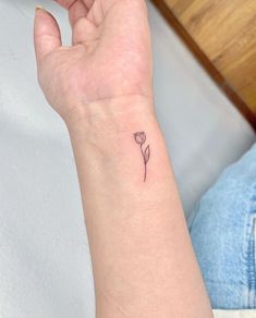 a woman's wrist with a small flower tattoo on her left hand and the word love written in it