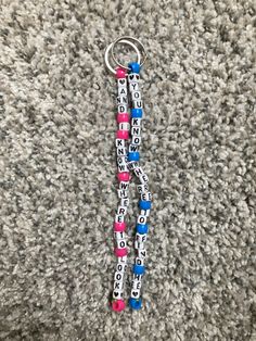 two beads are attached to a keychain on the carpet with words written all over it