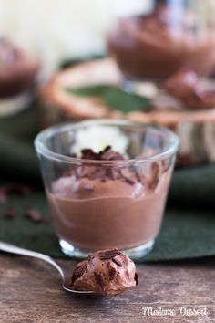 a spoon with some food in it on top of a table next to a glass bowl