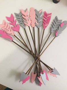 a bunch of pink and grey arrows on a white table next to a vase with flowers in it