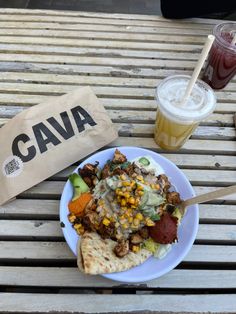 a white plate topped with food on top of a wooden table next to a drink