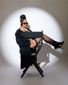 a woman sitting in a chair with her legs crossed, wearing black stockings and high heels