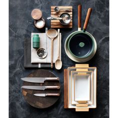 an assortment of kitchen utensils and wooden cutting boards on top of a table