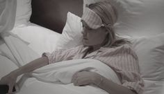 a woman laying in bed with her eyes closed and blind folded over her eyeglasses