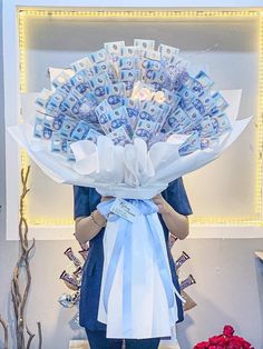 a woman holding a bouquet of money in front of a wall with lights on it