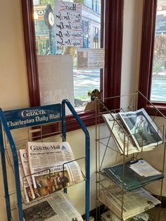 newspapers are stacked on metal racks in front of a window