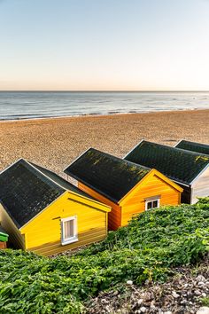 three small houses sitting on top of a beach next to the ocean