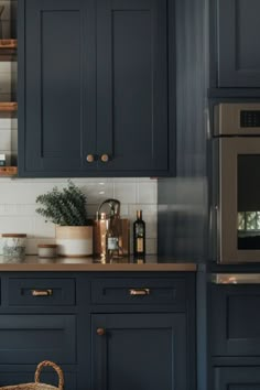 a kitchen with dark blue cabinets and gold handles