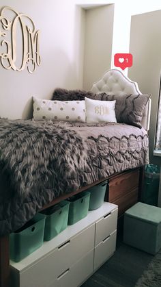 a bedroom with a bed, dressers and storage bins in front of it