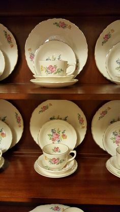 the china cabinet has many plates and cups on it, including one that is decorated with flowers