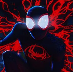 a spider - man with glowing eyes sits in front of a red background