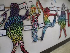 a group of people made out of different colored circles on a white wall in a school hallway