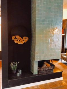 a fireplace in a living room next to a couch and table with two potted plants on it