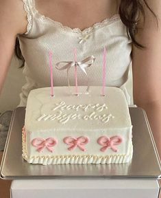 a woman is holding a birthday cake with candles in the shape of numbers and bows