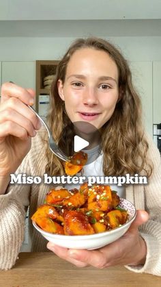 a woman holding a bowl of food with a spoon in her hand and the words miso butter pumpkin on it