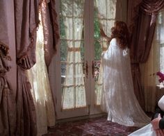 a woman in a wedding dress looking out the window