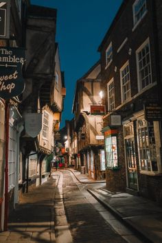 an empty street at night with shops on both sides