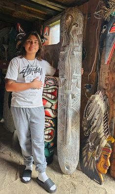 a young man standing next to some wooden carvings