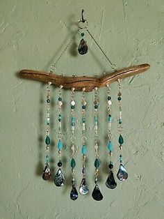 a wind chime hanging from a wooden branch with beads and tears on it