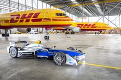 a race car is parked in front of an airplane