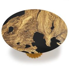 a round wooden object with black and gold paint on it's sides, sitting on a white surface