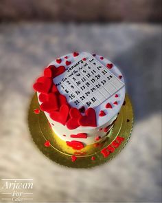 a white cake with red hearts sitting on top of a gold plated platter