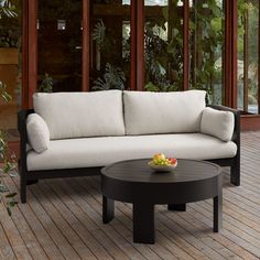 a black and white couch sitting on top of a wooden floor next to a table