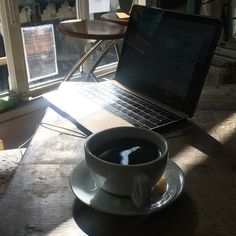 a cup of coffee sitting on top of a saucer next to a laptop computer