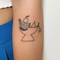 a woman's arm with a tattoo on it that has bananas and an apple in a bowl