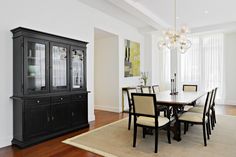 a dining room table and chairs in front of a black china cabinet with glass doors