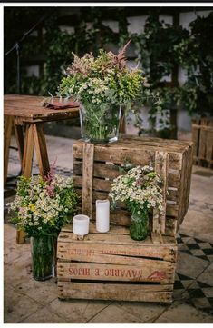 flowers are arranged in vases on wooden crates