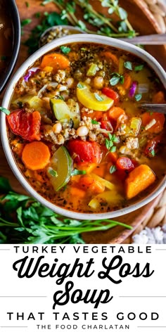 a bowl filled with turkey vegetable soup on top of a wooden table next to vegetables