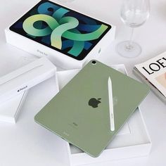 an apple tablet sitting on top of a table next to some books and wine glasses