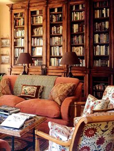 a living room filled with lots of furniture and bookshelves full of books on top of them