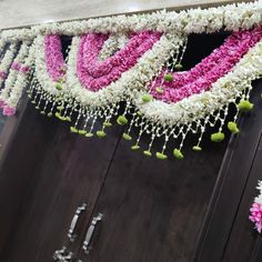 the door is decorated with pink and white flowers, beads and tassels hanging from it