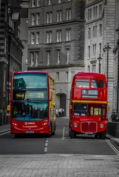 two red double decker buses driving down the street